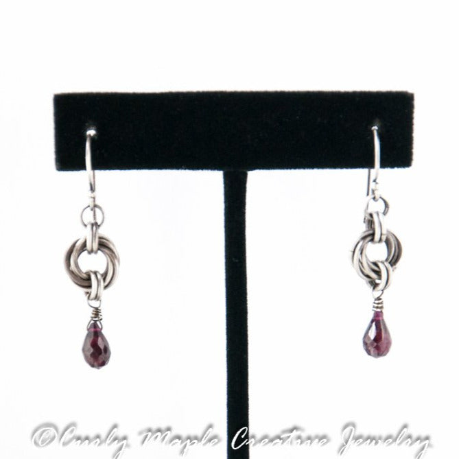 Garnet Silver Chainmaille Earrings hanging from a jewelry stand